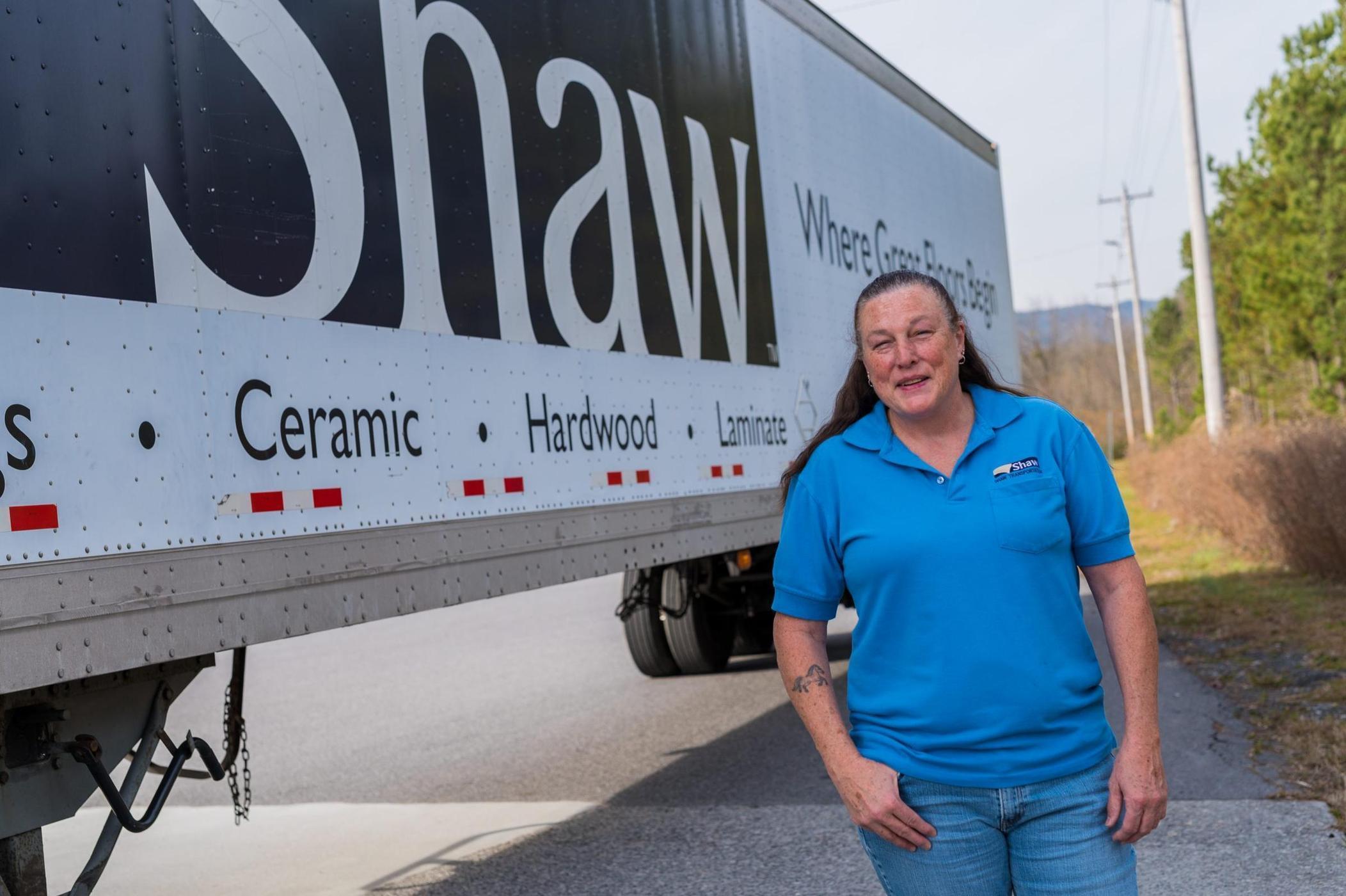 Female truck driver standing on the side of a Shaw semi truck